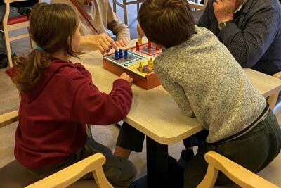 Deux personnes âgées qui jouent aux petits chevaux avec deux enfants - Agrandir l'image 2 sur 6, fenêtre modale