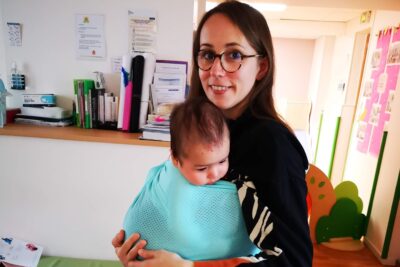 Une maman portant son enfant contre elle enveloppé dans un tissu accroché à elle - Agrandir l'image 1 sur 2, fenêtre modale