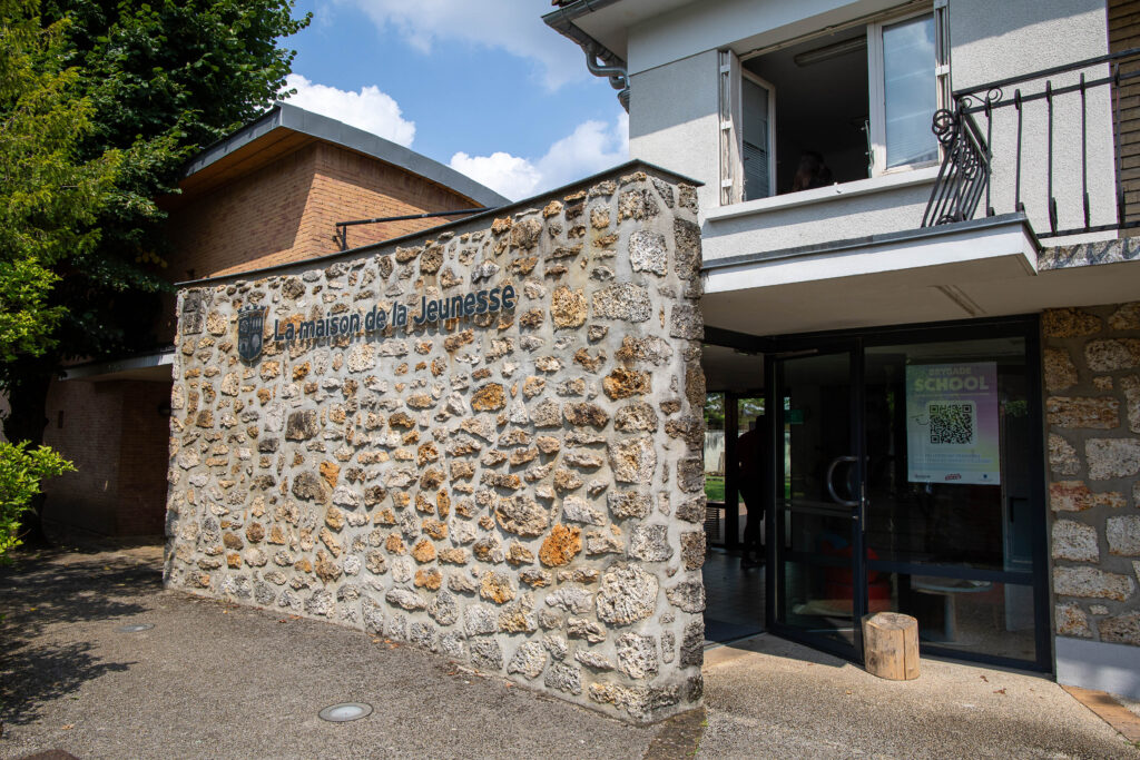Entrée d'un bâtiment avec mur en pierre sur lequel il est inscrit "La maison de la Jeunesse" - Agrandir l'image, fenêtre modale