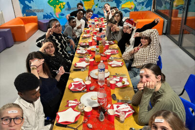Jeunes assis autour d'une grande table décorée pour Noël - Agrandir l'image 3 sur 12, fenêtre modale