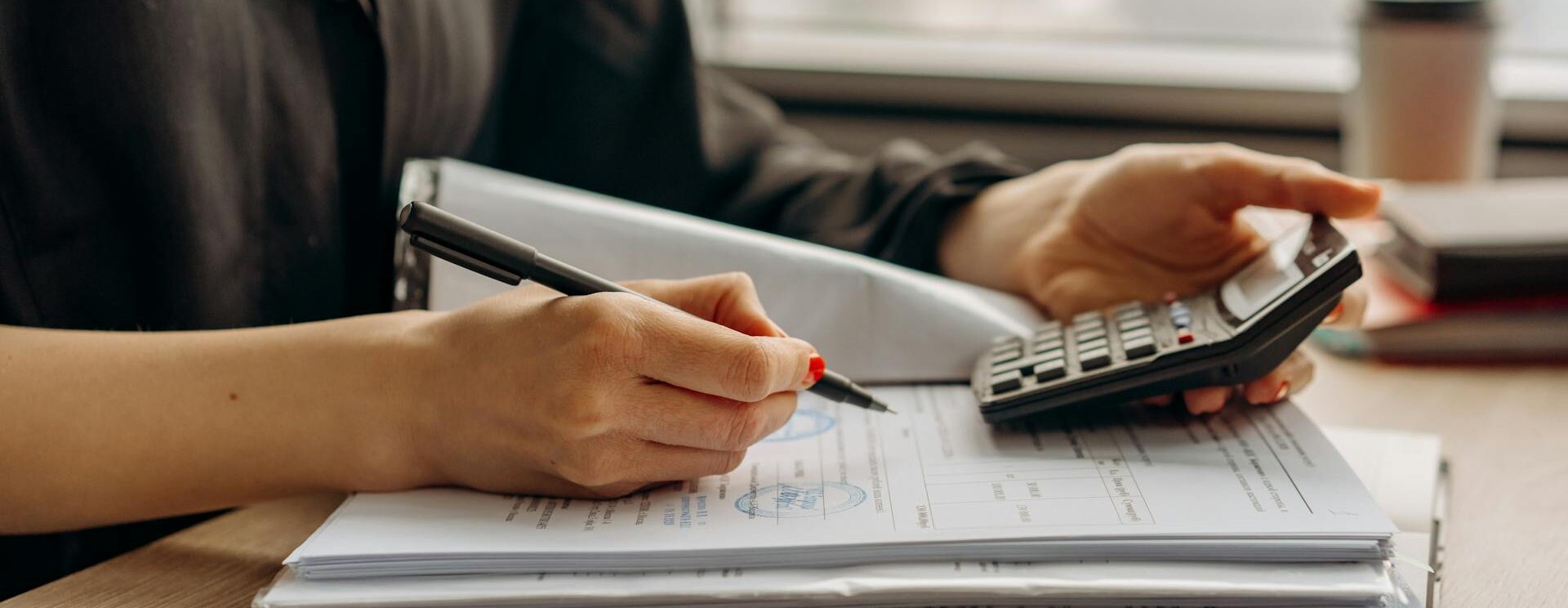 Main qui tient un stylo devant une calculatrice