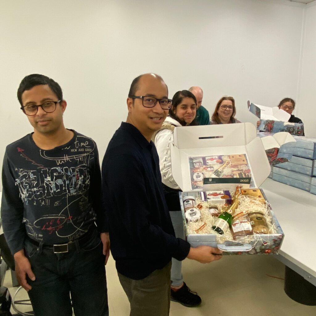 Homme qui tient un colis avec de la nourriture et une bouteille, accompagné d'autres personnes autour de lui - Agrandir l'image, fenêtre modale
