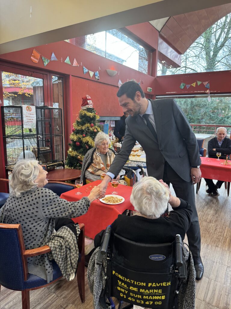 Monsieur le Maire qui serre la main d'une personne âgée assise à une table - Agrandir l'image, fenêtre modale