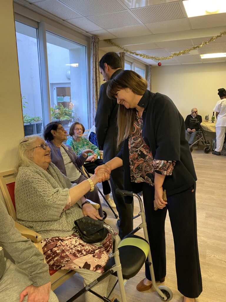 Une membre du Conseil Municipal qui serre la main d'une personne âgée - Agrandir l'image, fenêtre modale