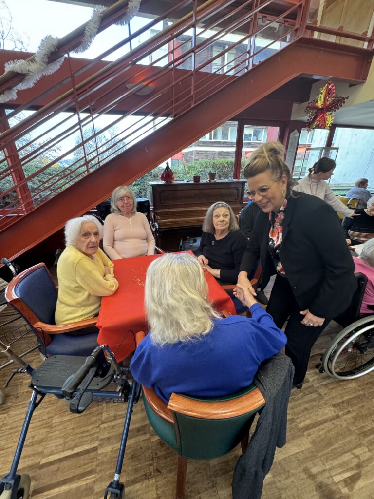 Membre du Conseil Municipal qui serre la main d'une personne âgée assise à une table - Agrandir l'image, fenêtre modale