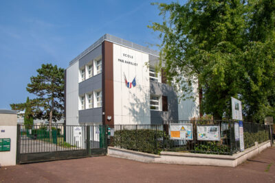 Bâtiment rénové du groupe scolaire Paul Barilliet, blanc avec du gris et du marron. Il y a un grand portail adjacent pour accéder au groupe scolaire. 


 - Agrandir l'image 3 sur 9, fenêtre modale